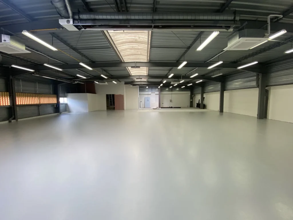 Sol en résine époxy appliqué dans un entrepôt industriel - finition lisse et résistante.